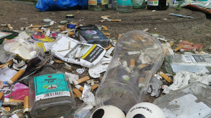 Das Augenpaar liegt zwischen Zigarettenstummeln, leeren Schnapsflaschen und anderem Müll.